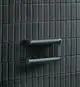 Papierrollenhalter aus chromfarbenem Metall, montiert an einer dunklen Fliesenwand, von der Marke Ideal Standard. Das Design zeigt eine einfache, funktionale Form ohne Deckel.